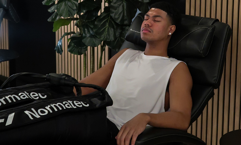 A man relaxing in a massage recliner using Normatec compression therapy in the Adelaide Club’s Recovery Retreat.