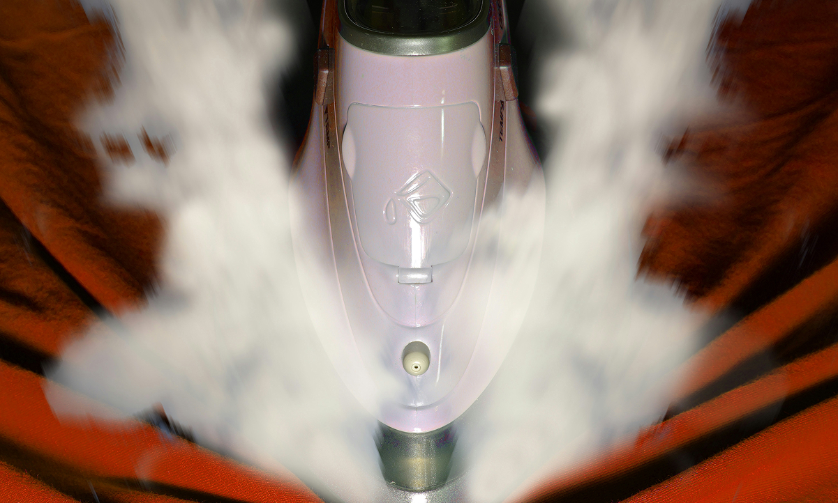 A steam iron releasing hot steam while pressing a red garment, representing the Adelaide Club’s laundry service.